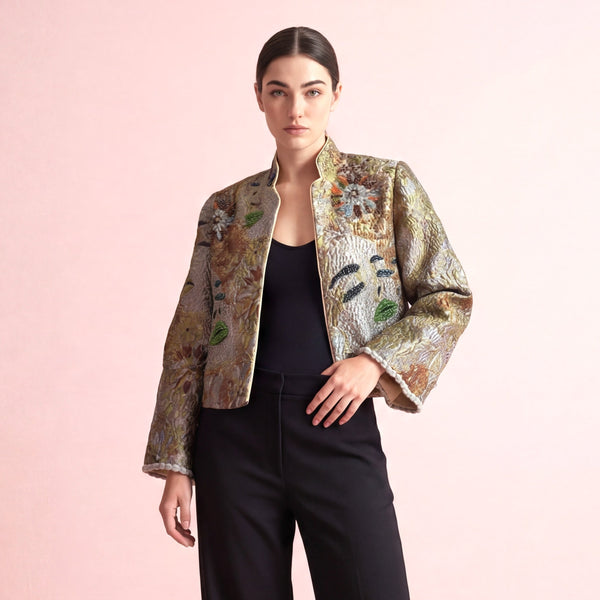 Woman wearing a patterned jacket and black pants on a pink background