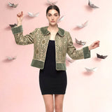 Woman wearing a green patterned jacket over a black dress with paper boats floating around on a pink background