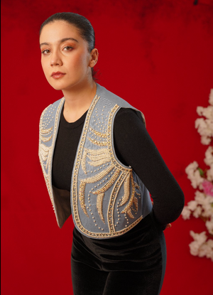 Woman wearing a decorative vest over a black outfit against a red background